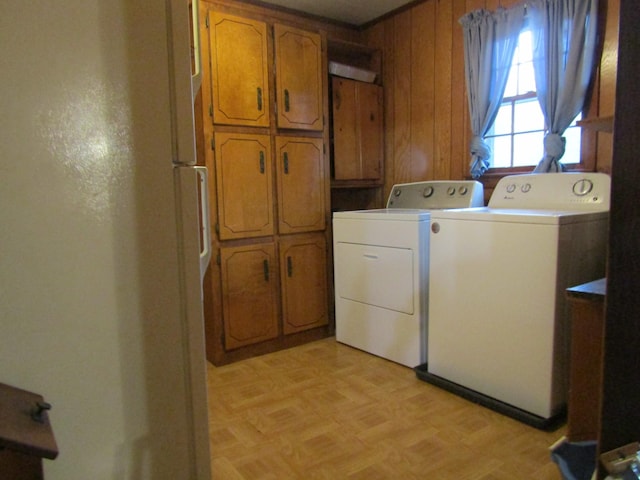 laundry room with washer and clothes dryer, cabinets, wooden walls, and light parquet floors