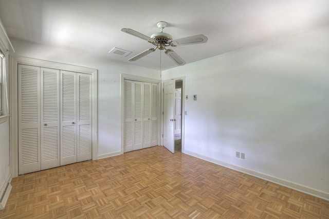 unfurnished bedroom with visible vents, two closets, a ceiling fan, and baseboards