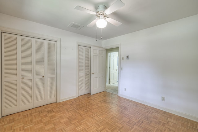 unfurnished bedroom with light parquet floors, two closets, and ceiling fan