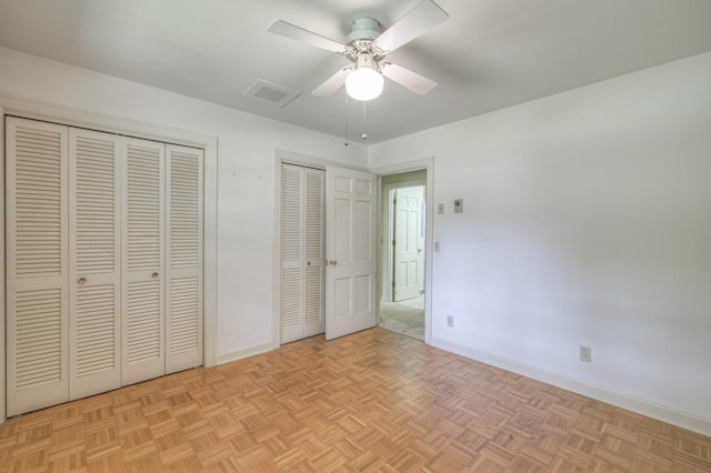 unfurnished bedroom with multiple closets, visible vents, ceiling fan, and baseboards