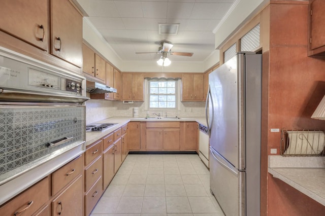 kitchen with tasteful backsplash, light countertops, appliances with stainless steel finishes, ornamental molding, and under cabinet range hood