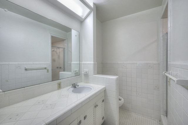 bathroom featuring tile walls, walk in shower, toilet, and vanity