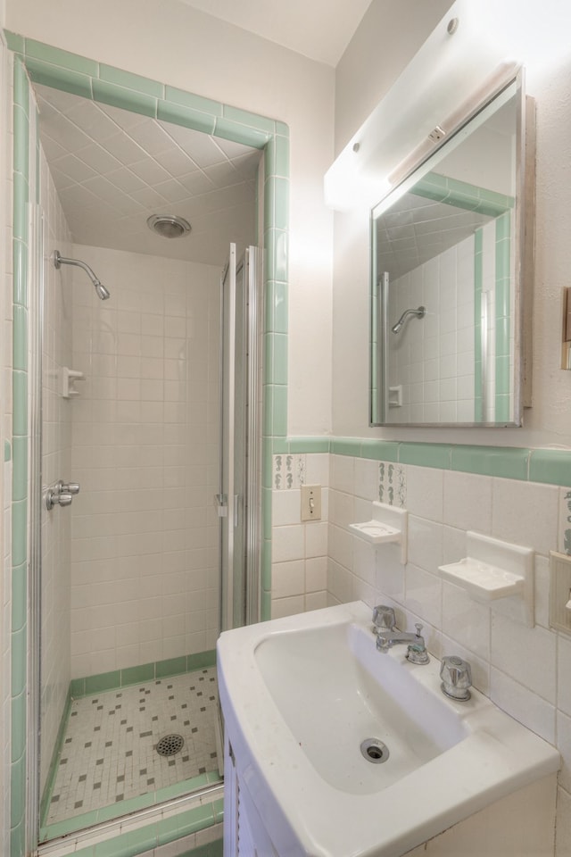 bathroom with tile walls, a shower with shower door, vanity, and tasteful backsplash