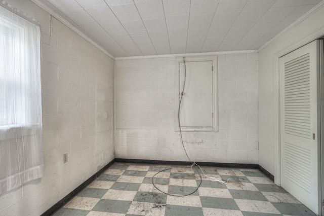 unfurnished room with ornamental molding, plenty of natural light, concrete block wall, and tile patterned floors