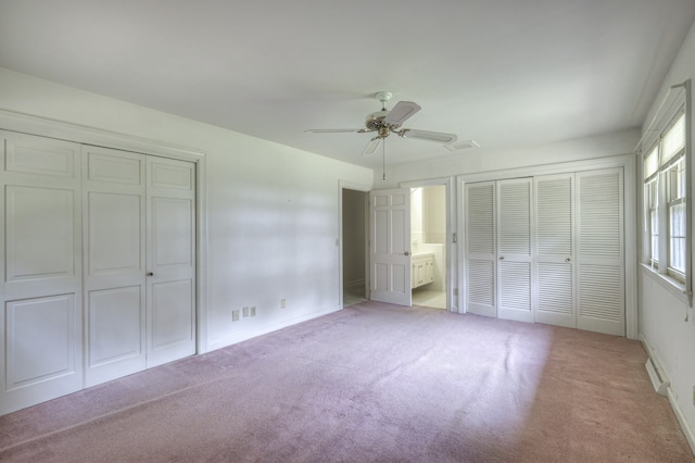 unfurnished bedroom featuring ensuite bath, ceiling fan, a baseboard heating unit, two closets, and light colored carpet