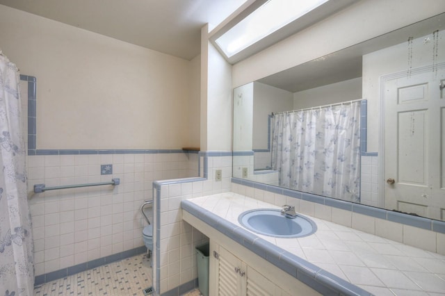 bathroom with a wainscoted wall, tile patterned flooring, vanity, and tile walls