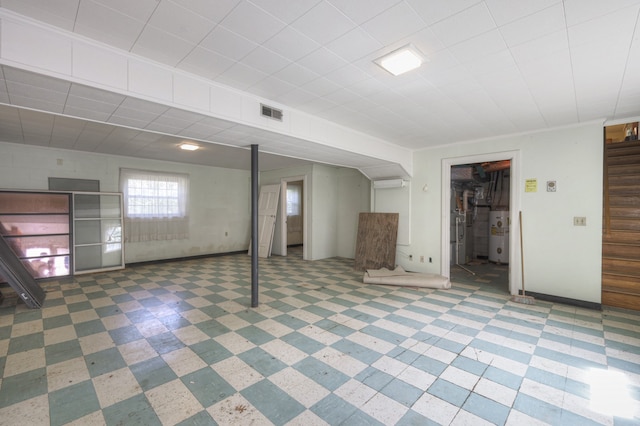 basement featuring water heater and light tile patterned flooring