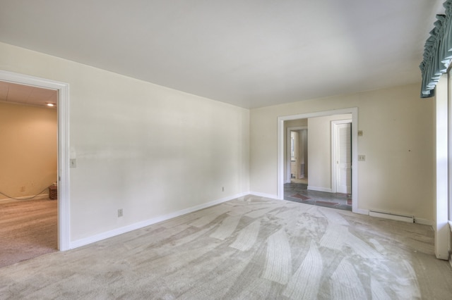 spare room with light carpet and a baseboard heating unit