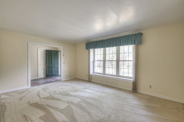 spare room with a baseboard heating unit and light colored carpet