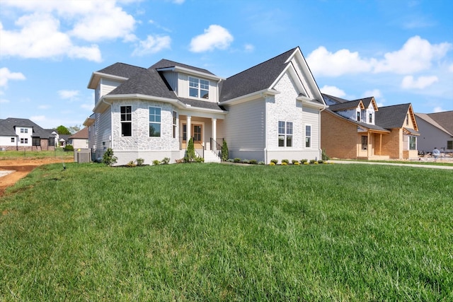 view of front of home featuring central AC, brick siding, a shingled roof, stone siding, and a front lawn