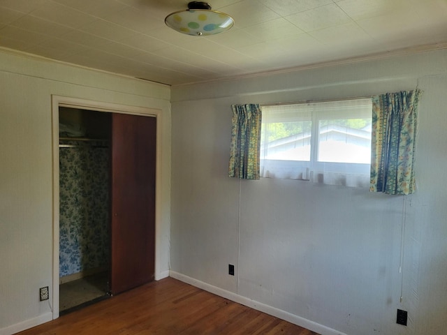 unfurnished bedroom featuring a closet, wood finished floors, and baseboards