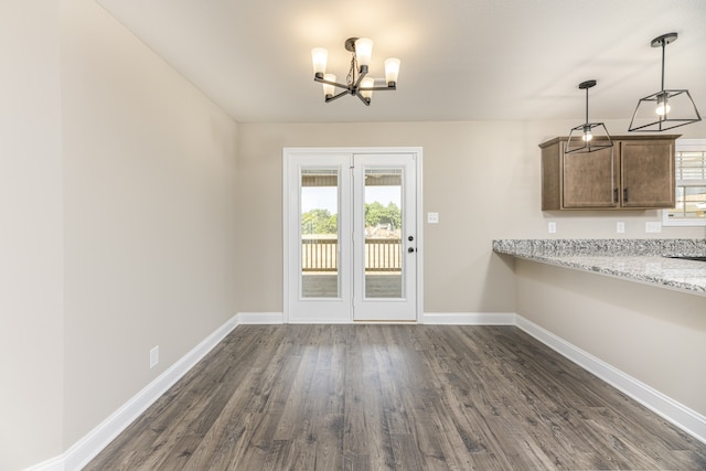 unfurnished dining area featuring dark wood-type flooring and an inviting chandelier