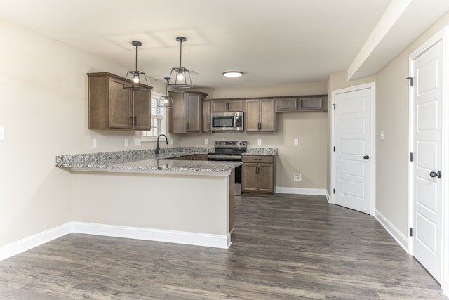 kitchen featuring light stone counters, dark hardwood / wood-style floors, kitchen peninsula, decorative light fixtures, and appliances with stainless steel finishes