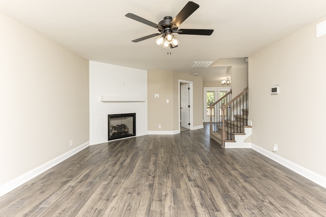 unfurnished living room with a large fireplace, ceiling fan, and dark wood-type flooring