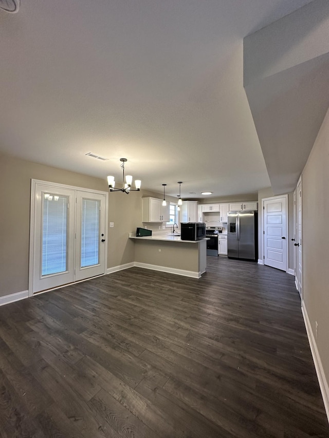 unfurnished living room featuring dark hardwood / wood-style floors, sink, and an inviting chandelier