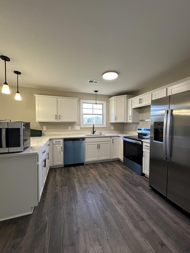 kitchen featuring appliances with stainless steel finishes, white cabinetry, pendant lighting, and sink