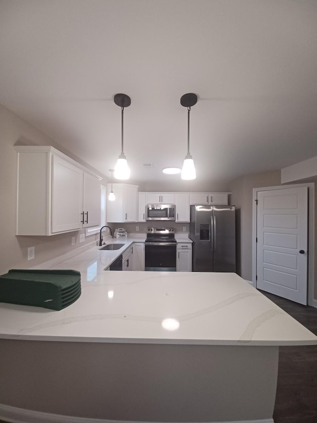 kitchen with sink, kitchen peninsula, pendant lighting, white cabinets, and appliances with stainless steel finishes