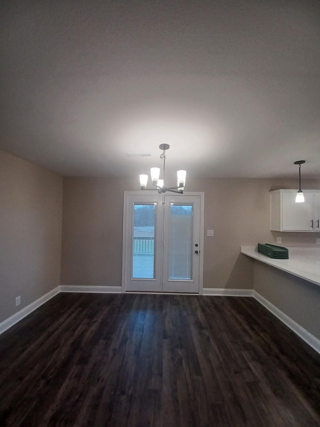 unfurnished dining area with a notable chandelier and dark wood-type flooring