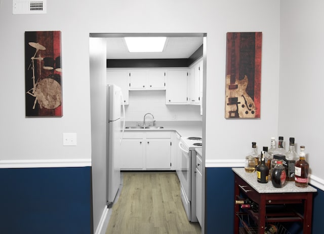 kitchen featuring white appliances, light hardwood / wood-style floors, white cabinetry, sink, and decorative backsplash