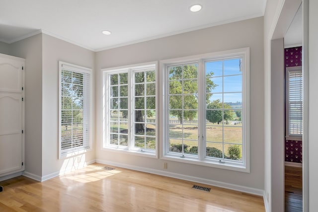 entryway with crown molding, a healthy amount of sunlight, and light hardwood / wood-style flooring