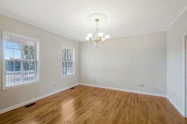 spare room featuring light wood-type flooring, a wealth of natural light, a notable chandelier, and ornamental molding