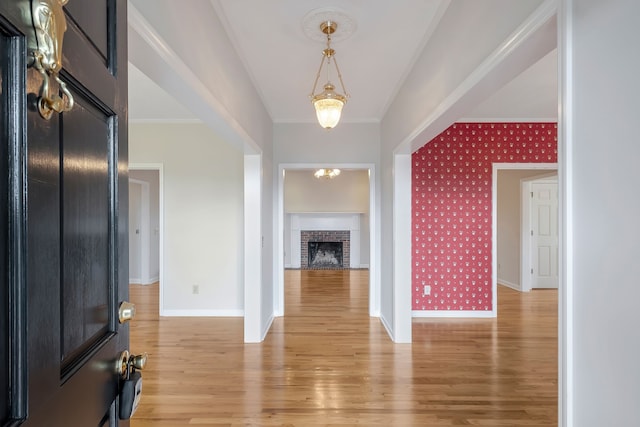 foyer entrance featuring a fireplace, ornamental molding, and hardwood / wood-style flooring