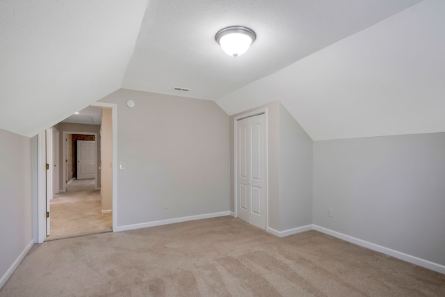 bonus room featuring light carpet, vaulted ceiling, and a textured ceiling