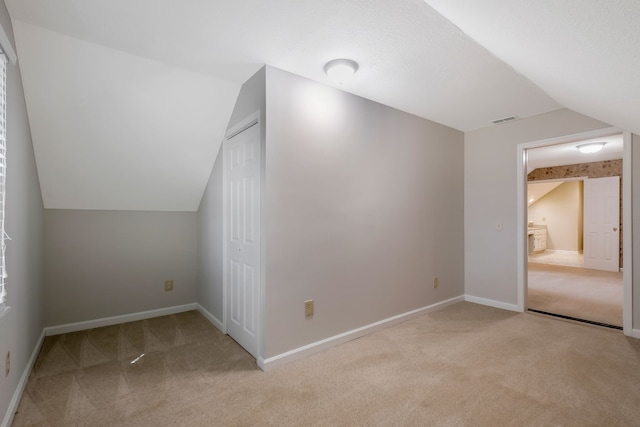 bonus room with light carpet, vaulted ceiling, and a textured ceiling