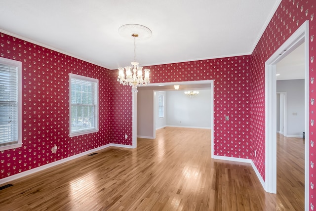 unfurnished dining area with ornamental molding, an inviting chandelier, and hardwood / wood-style floors