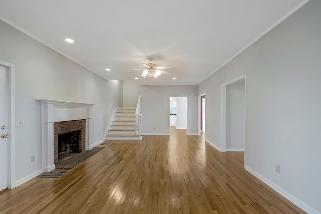 unfurnished living room featuring a fireplace, crown molding, light hardwood / wood-style flooring, and ceiling fan