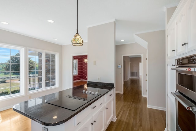 kitchen featuring a wealth of natural light, stainless steel double oven, hardwood / wood-style flooring, and white cabinets