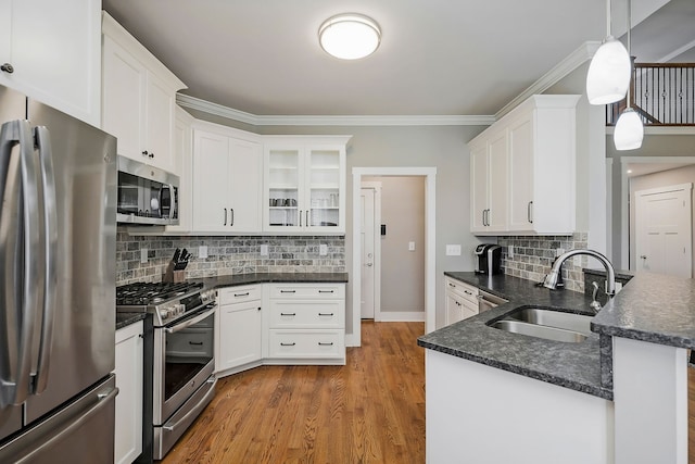 kitchen with tasteful backsplash, stainless steel appliances, wood-type flooring, sink, and hanging light fixtures