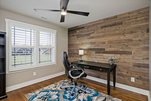 office area with wooden walls, ceiling fan, dark hardwood / wood-style floors, and a healthy amount of sunlight