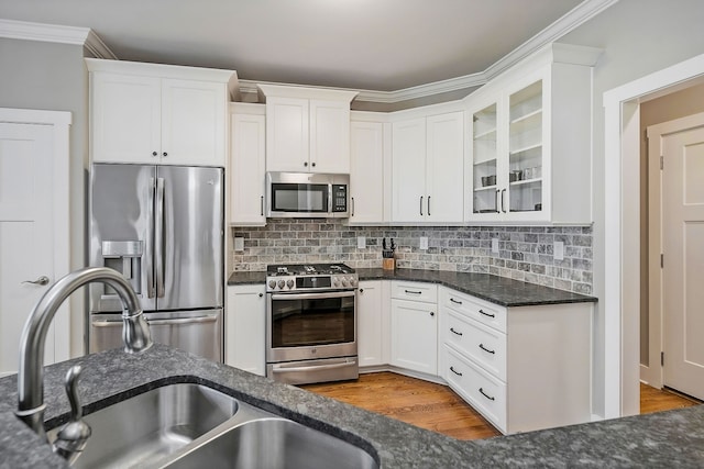 kitchen with wood-type flooring, backsplash, stainless steel appliances, sink, and white cabinets