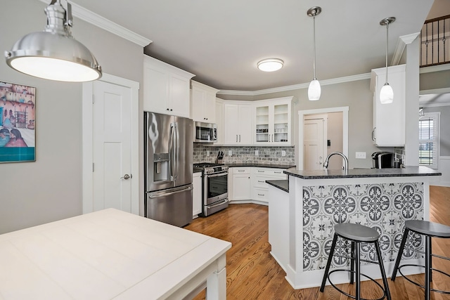 kitchen featuring a kitchen breakfast bar, decorative light fixtures, light hardwood / wood-style flooring, appliances with stainless steel finishes, and kitchen peninsula