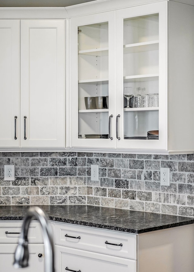 kitchen featuring white cabinets, backsplash, and dark stone counters