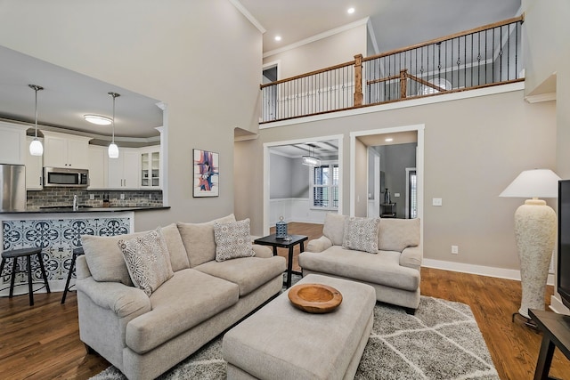 living room with crown molding, a high ceiling, and dark wood-type flooring