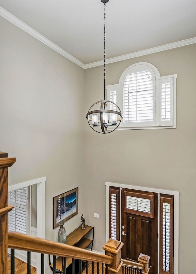 entryway with wood-type flooring, an inviting chandelier, and ornamental molding