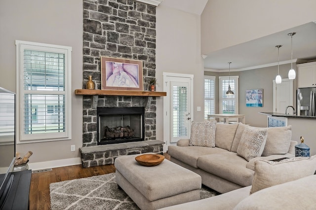 living room with crown molding, a towering ceiling, dark hardwood / wood-style flooring, and a fireplace