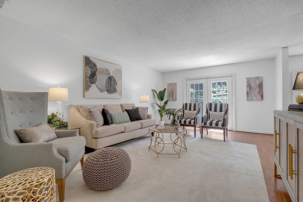 living room with a textured ceiling, french doors, and hardwood / wood-style flooring