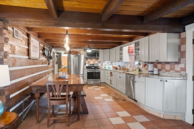 kitchen with beam ceiling, tasteful backsplash, hanging light fixtures, stainless steel appliances, and white cabinets