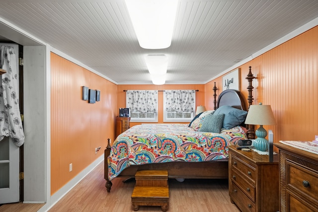 bedroom with wood walls and light hardwood / wood-style floors