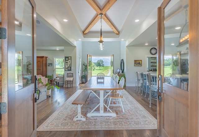 dining room with dark wood-type flooring, lofted ceiling with beams, and a healthy amount of sunlight