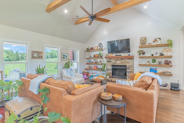 living room with high vaulted ceiling, wood-type flooring, ceiling fan, and a stone fireplace