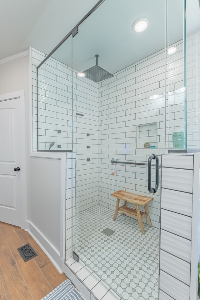 bathroom featuring ornamental molding, wood-type flooring, and an enclosed shower