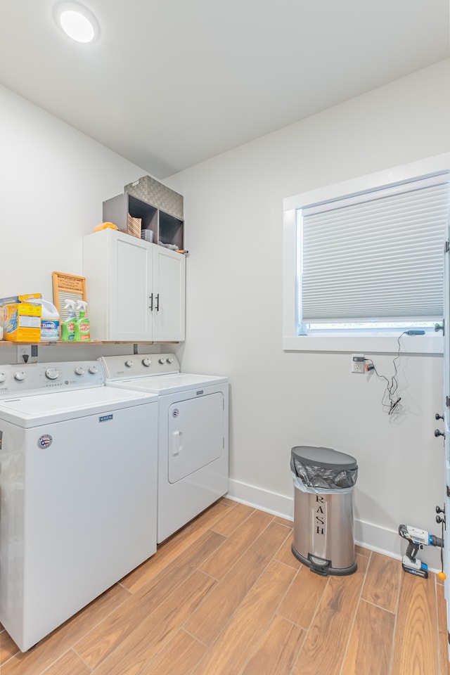 clothes washing area with washer and dryer, cabinets, and light hardwood / wood-style flooring