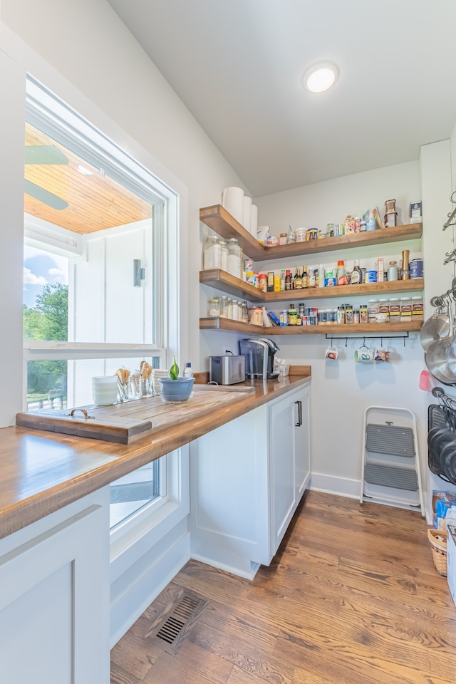 kitchen featuring butcher block countertops, wood-type flooring, and white cabinetry