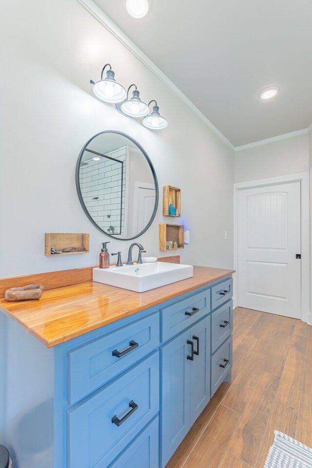 bathroom featuring wood-type flooring, ornamental molding, and vanity