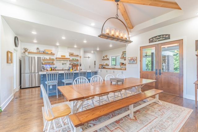 dining room with lofted ceiling with beams, french doors, and light hardwood / wood-style flooring