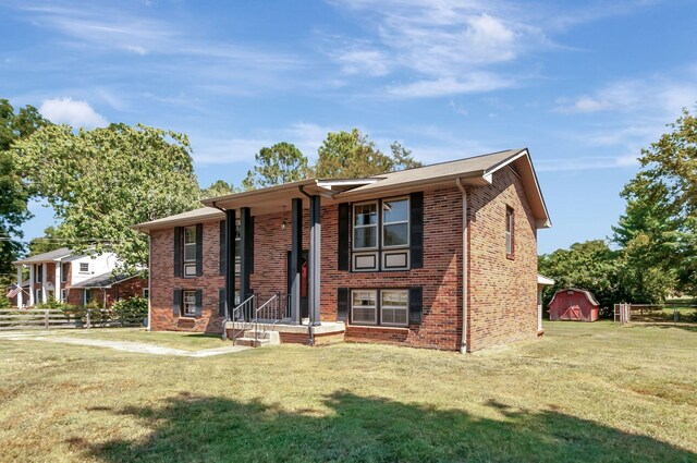 raised ranch featuring a front lawn and a storage unit